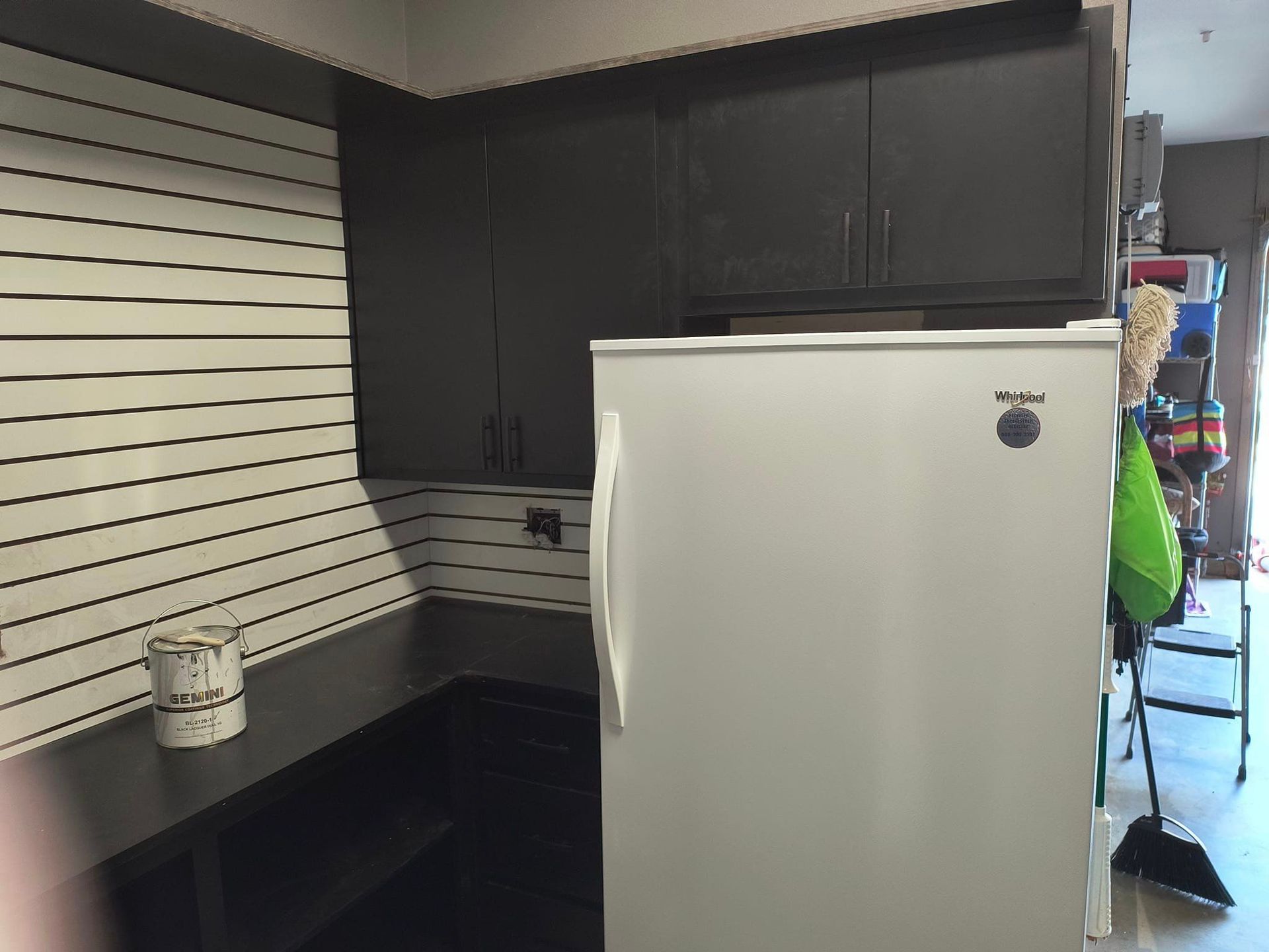 A white refrigerator in a kitchen with black cabinets