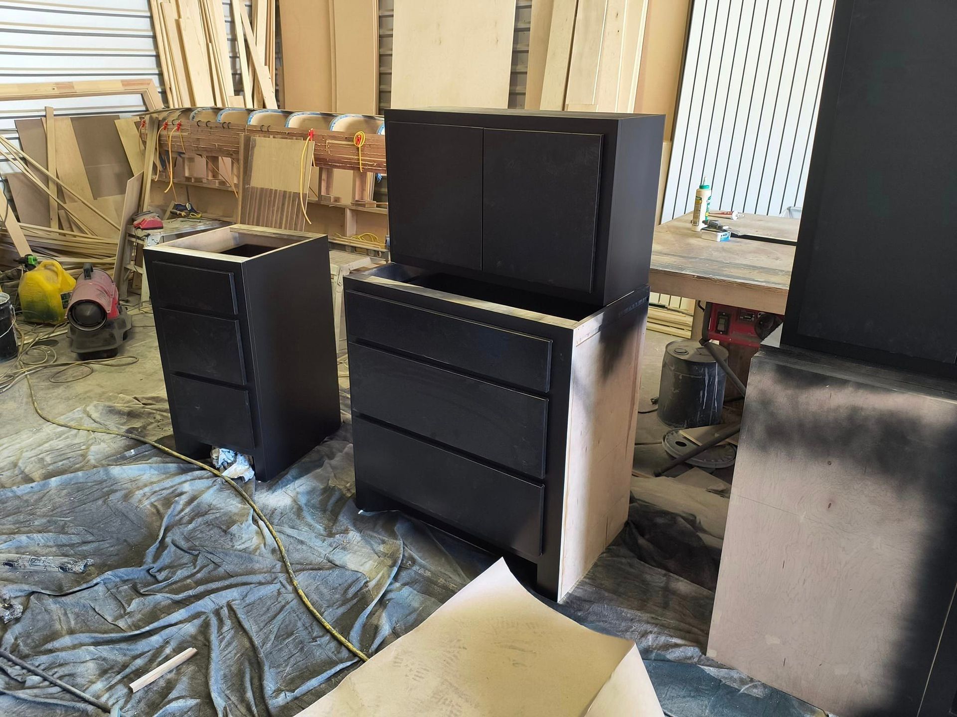 A couple of black cabinets are sitting on top of each other in a room.
