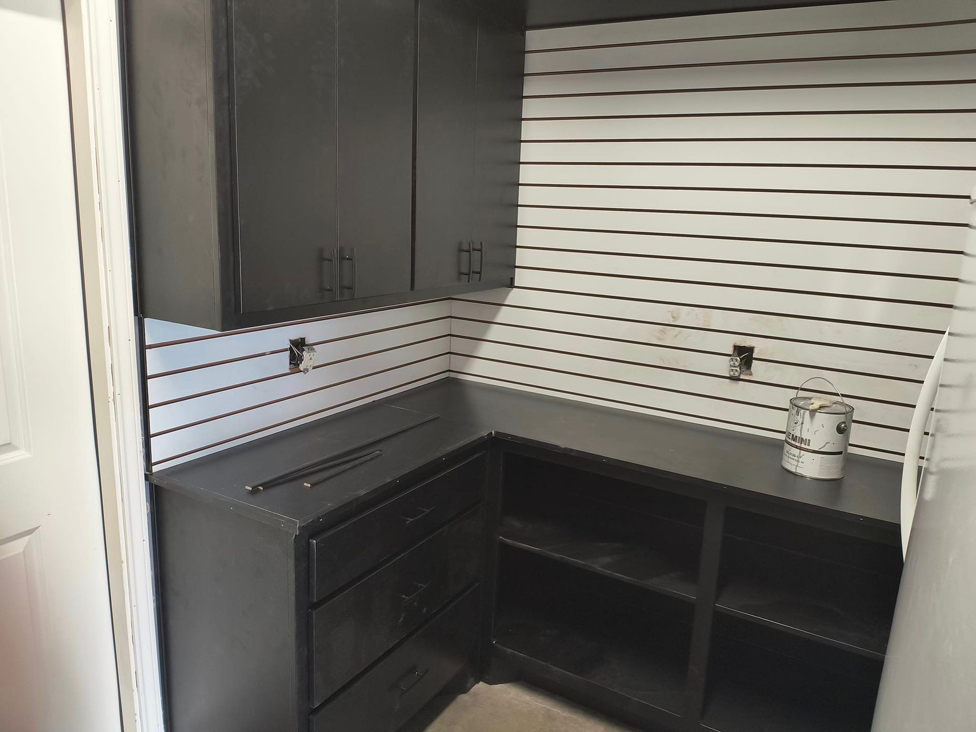 A kitchen with black cabinets and white stripes on the wall