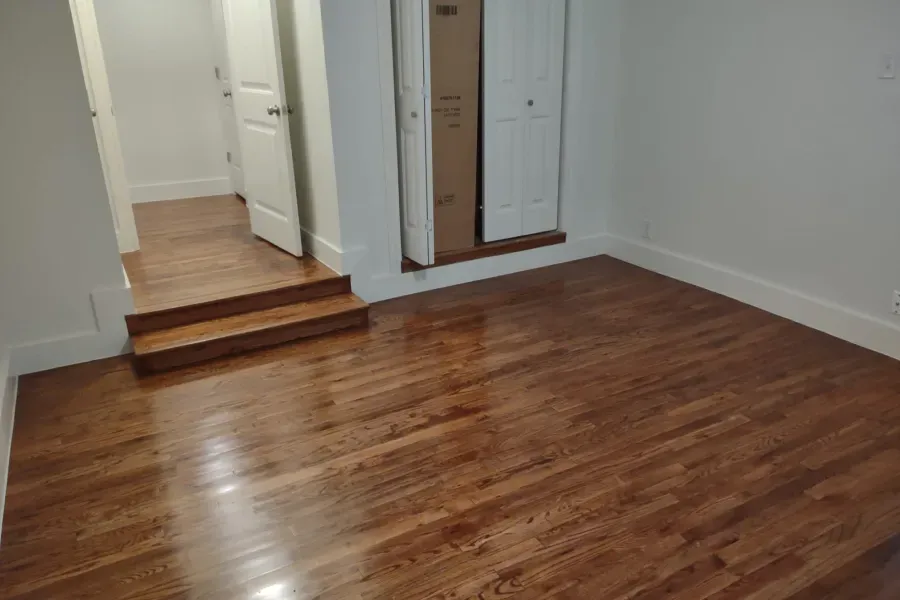 An empty room with hardwood floors and white walls