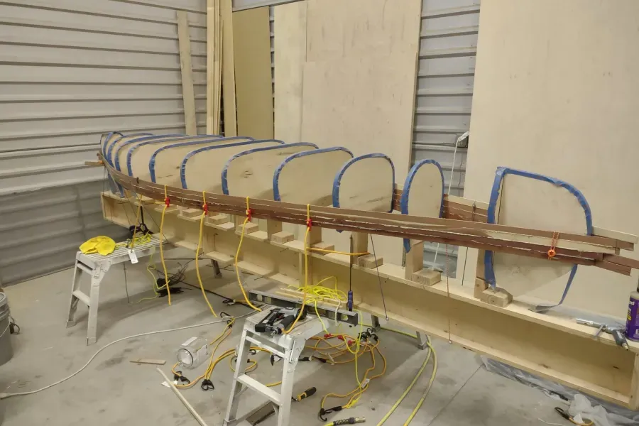 A wooden boat is being built in a garage.