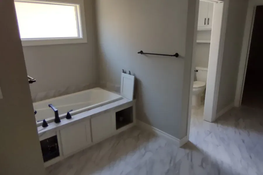 A bathroom with a tub , toilet and window.