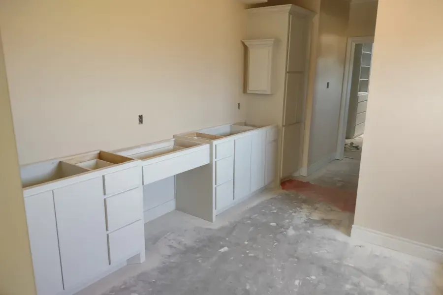 A kitchen under construction with white cabinets and a sink.