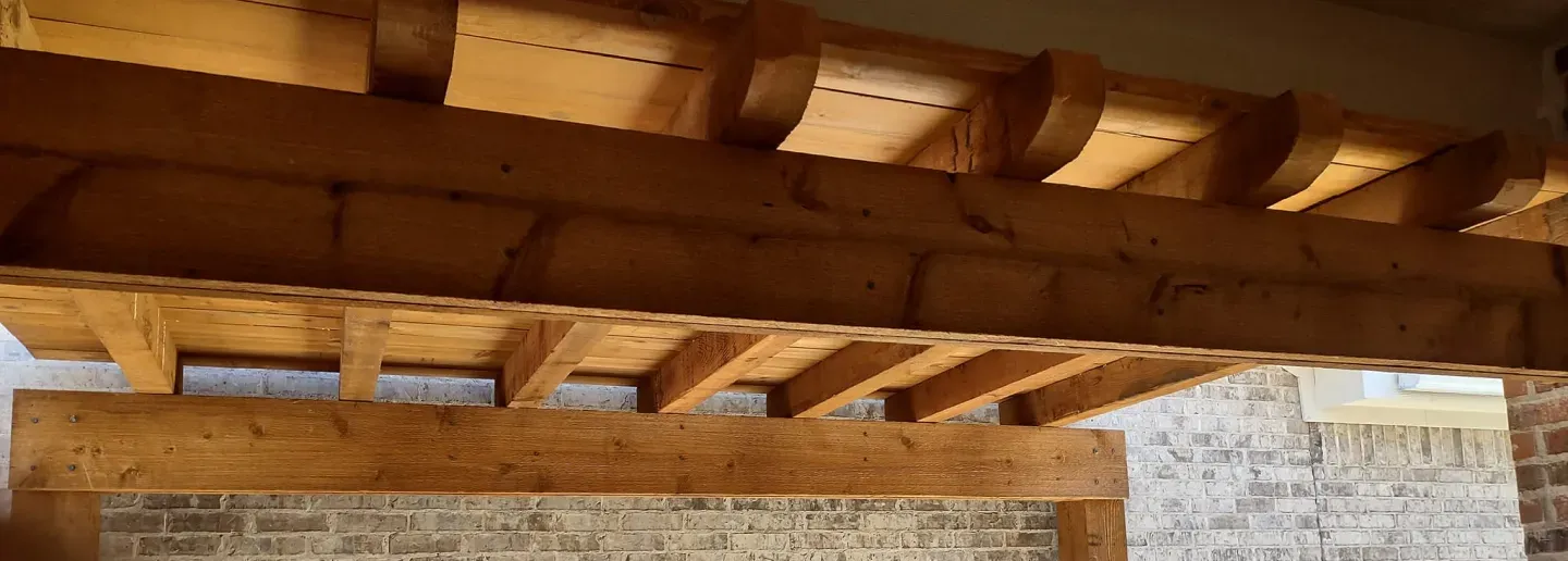 A close up of a wooden structure with a brick wall in the background.