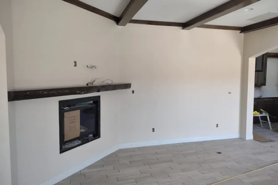 An empty living room with a fireplace and a shelf
