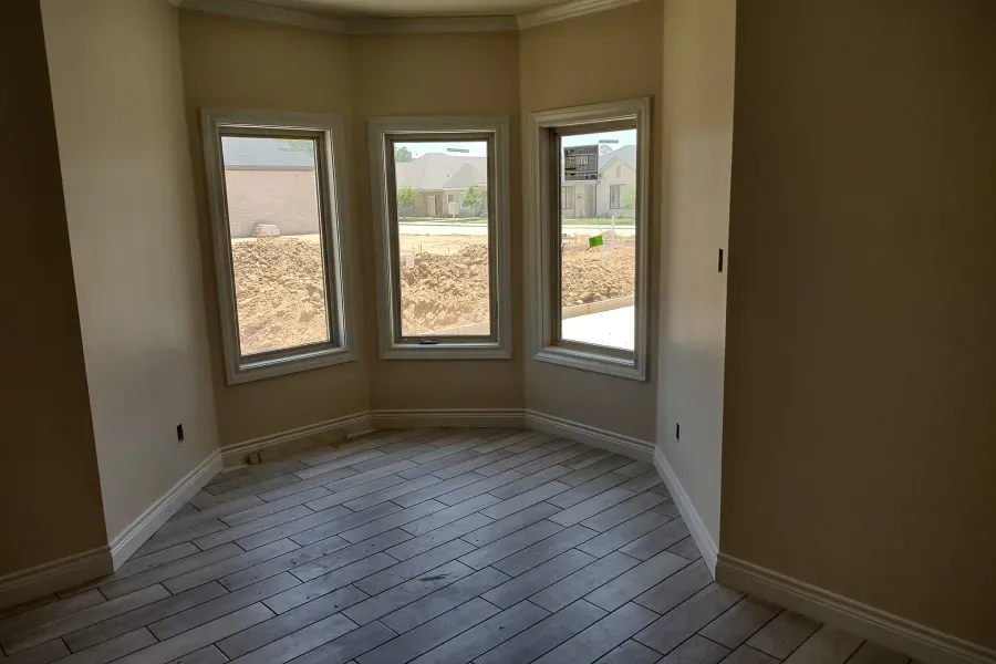 An empty room with three windows and a tiled floor.