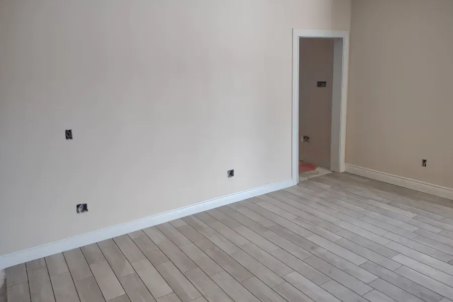 An empty room with a wooden floor and white walls.