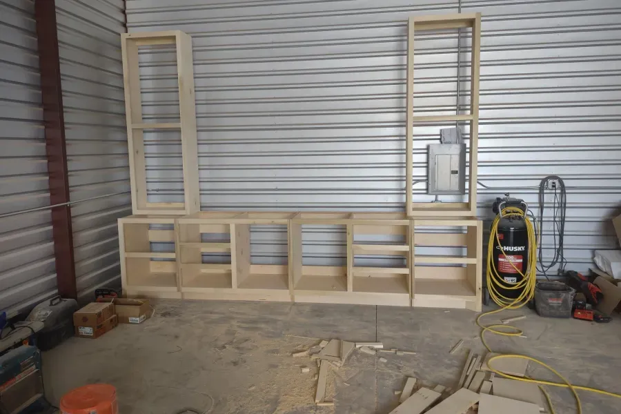 A wooden shelf is being built in a garage.