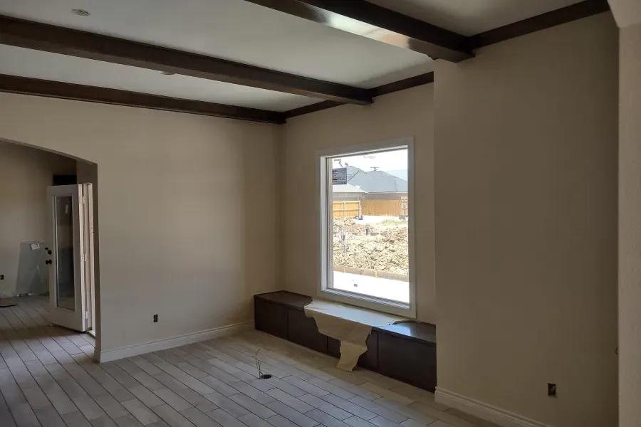 An empty living room with a window and a bench.