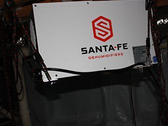 Santa Fe dehumidifier unit with white front panel and red logo, mounted above a dark opening