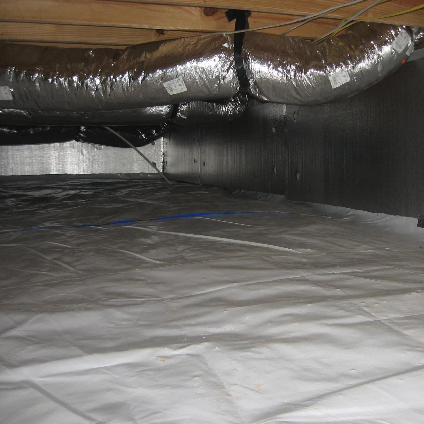 Attic crawlspace with insulated ductwork and a white vapor barrier floor