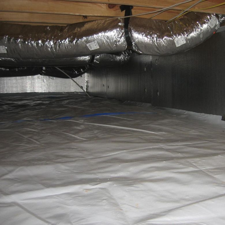 Attic crawlspace with insulated ductwork and a white vapor barrier floor
