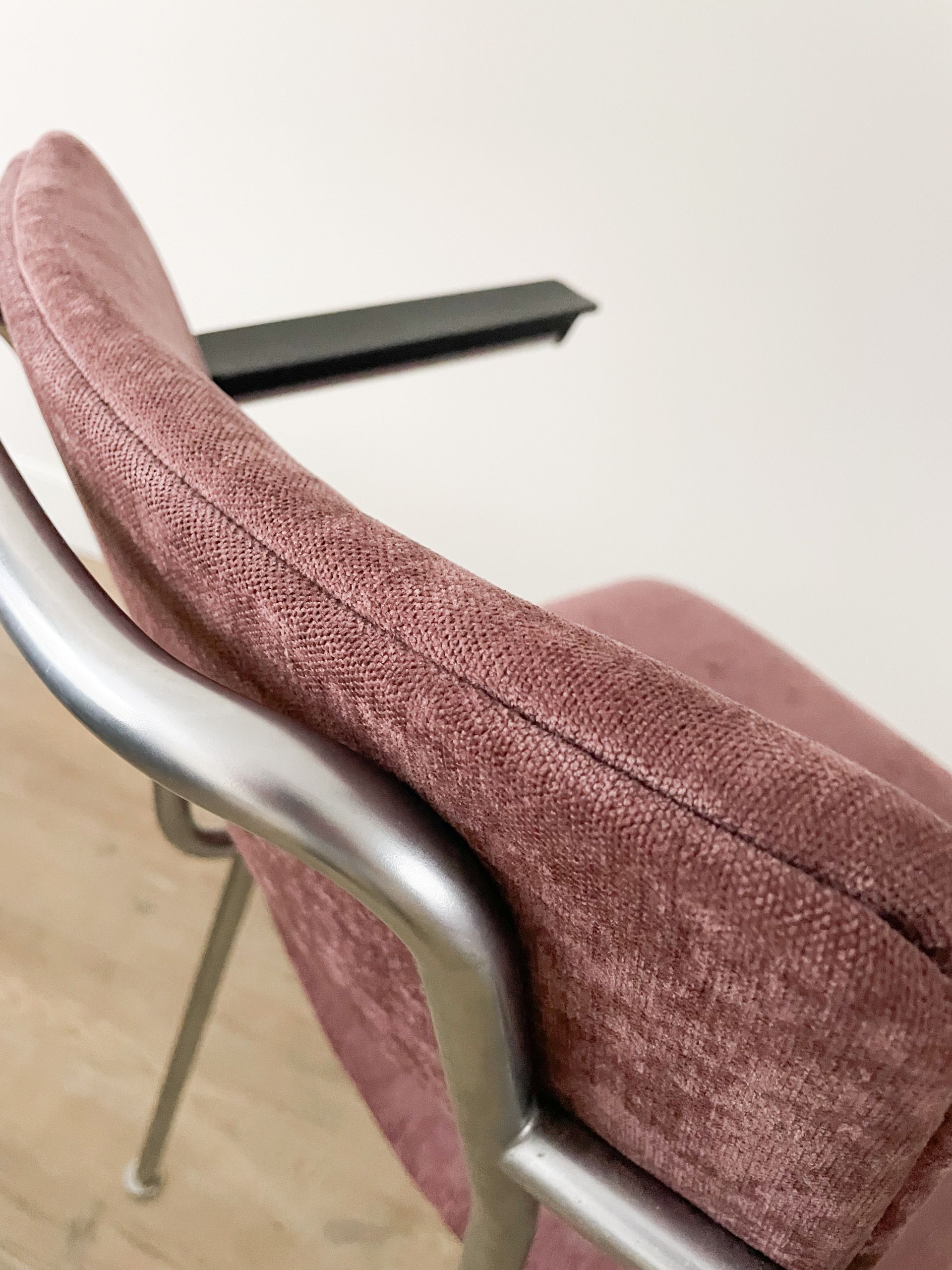 Mauve fabric-covered chair with a silver metal frame and black armrest against a light background