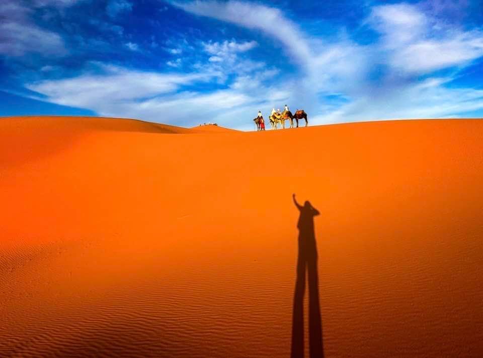 Travel Vacations to Morocco - A shadow of a person riding a camel in the Saharan Desert.