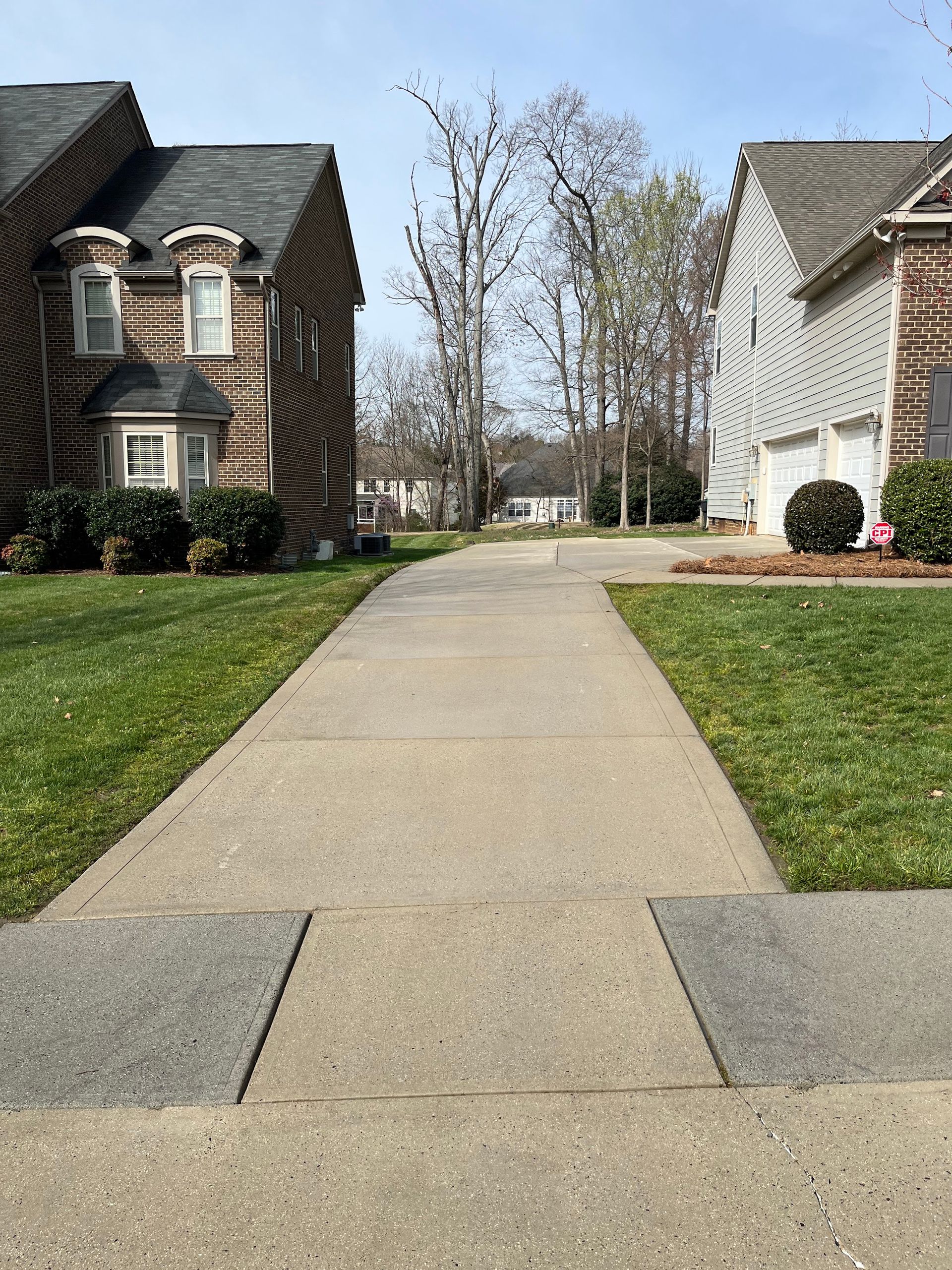 A sidewalk leading to two houses in a residential area.