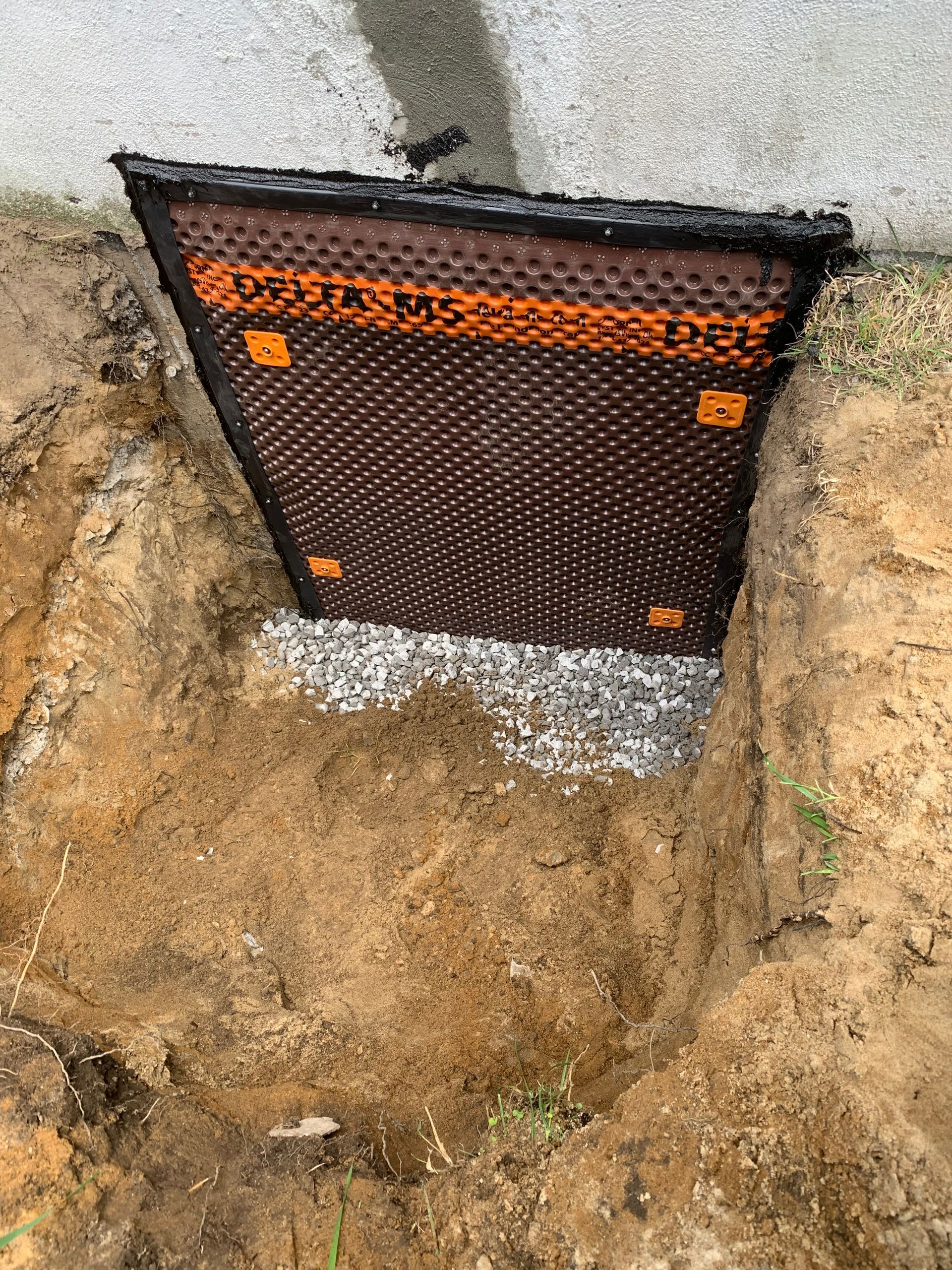 Un système de drainage est en train d'être installé dans un trou dans le sol.