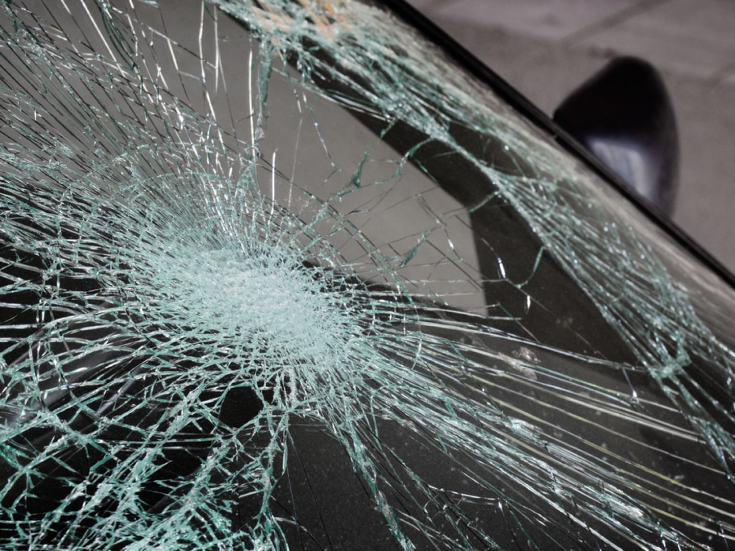 Cracked car windshield with radial fractures spreading from a central impact point.