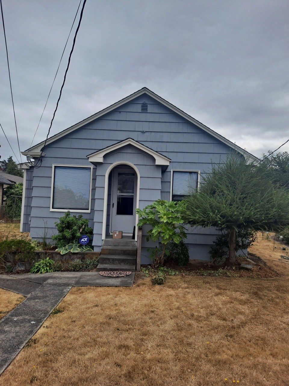 Single‑story house with fresh gray exterior paint and white trim around windows and entryway.