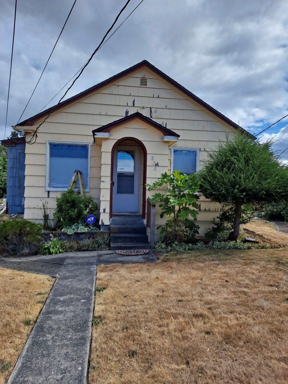 Single‑story home with chipped and faded yellow paint in need of a new paint job.
