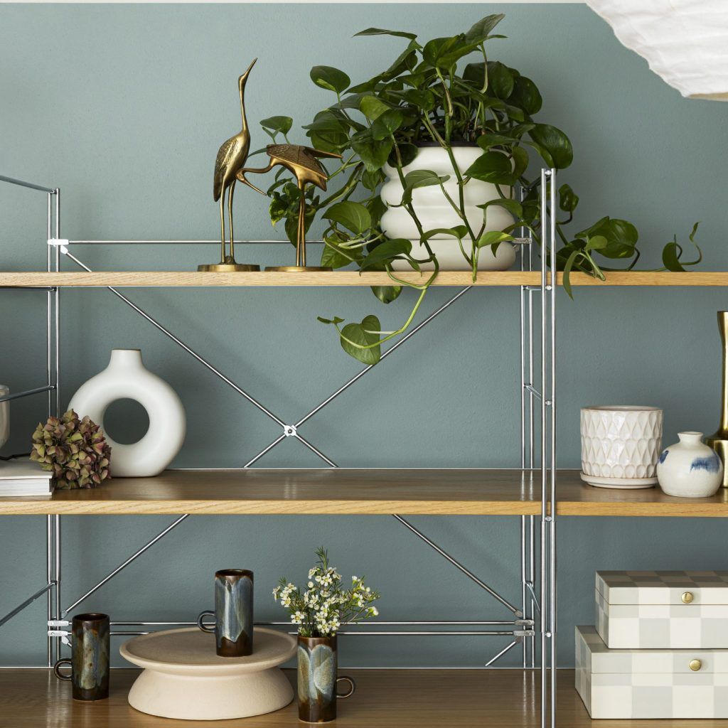 a green painted wall with a bookshelf and white decorated pieces