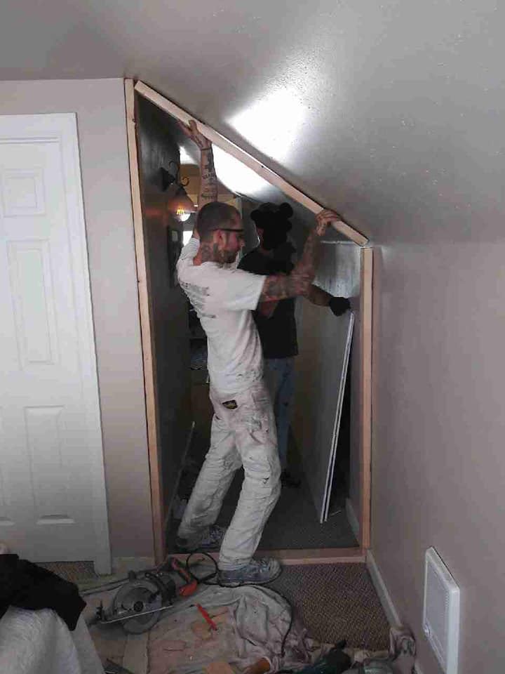 A Paint‑Right Painting employee replaces the drywall of a small wall against a slanted roof.