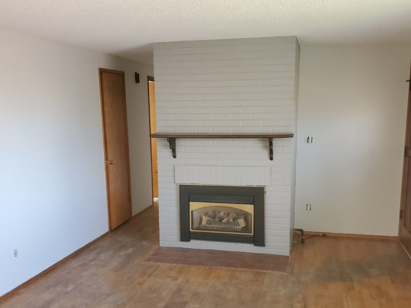 The after image of a formerly red-brick fireplace that is freshly painted white. 