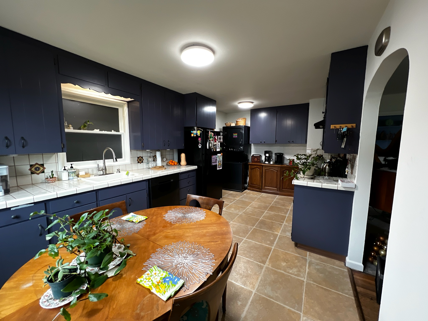 Kitchen with blue cabinets, round wooden table, and beige tile floor.