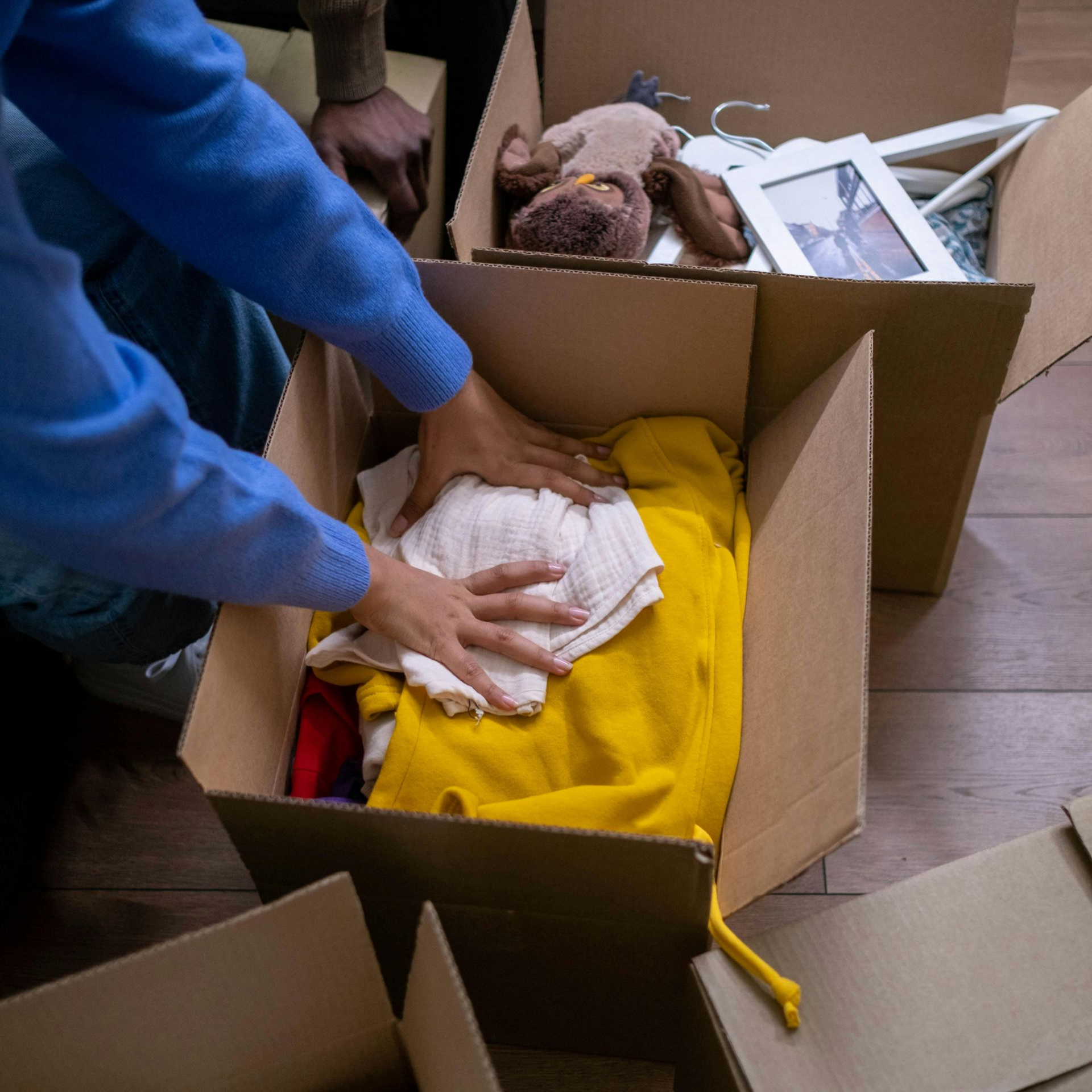 People packing clothes and old pictures into cardboard boxes during an estate cleanout. 