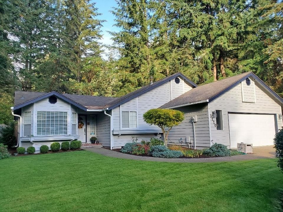 Light gray home with white trim, a white garage door, and a neatly landscaped front yard.