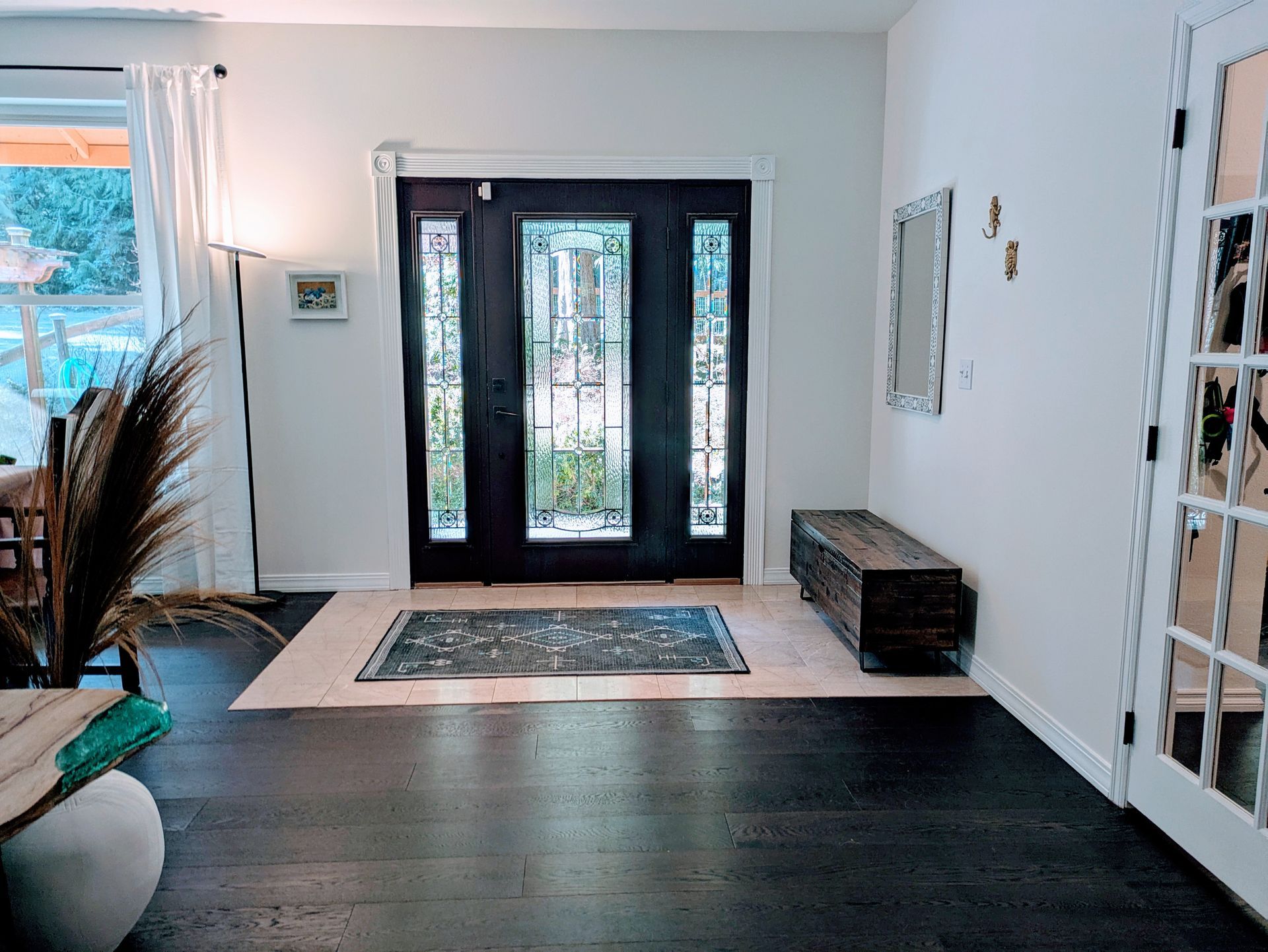 The off-white walls in a living room and entryway look crisp and bright against a dark floor and door frame. 