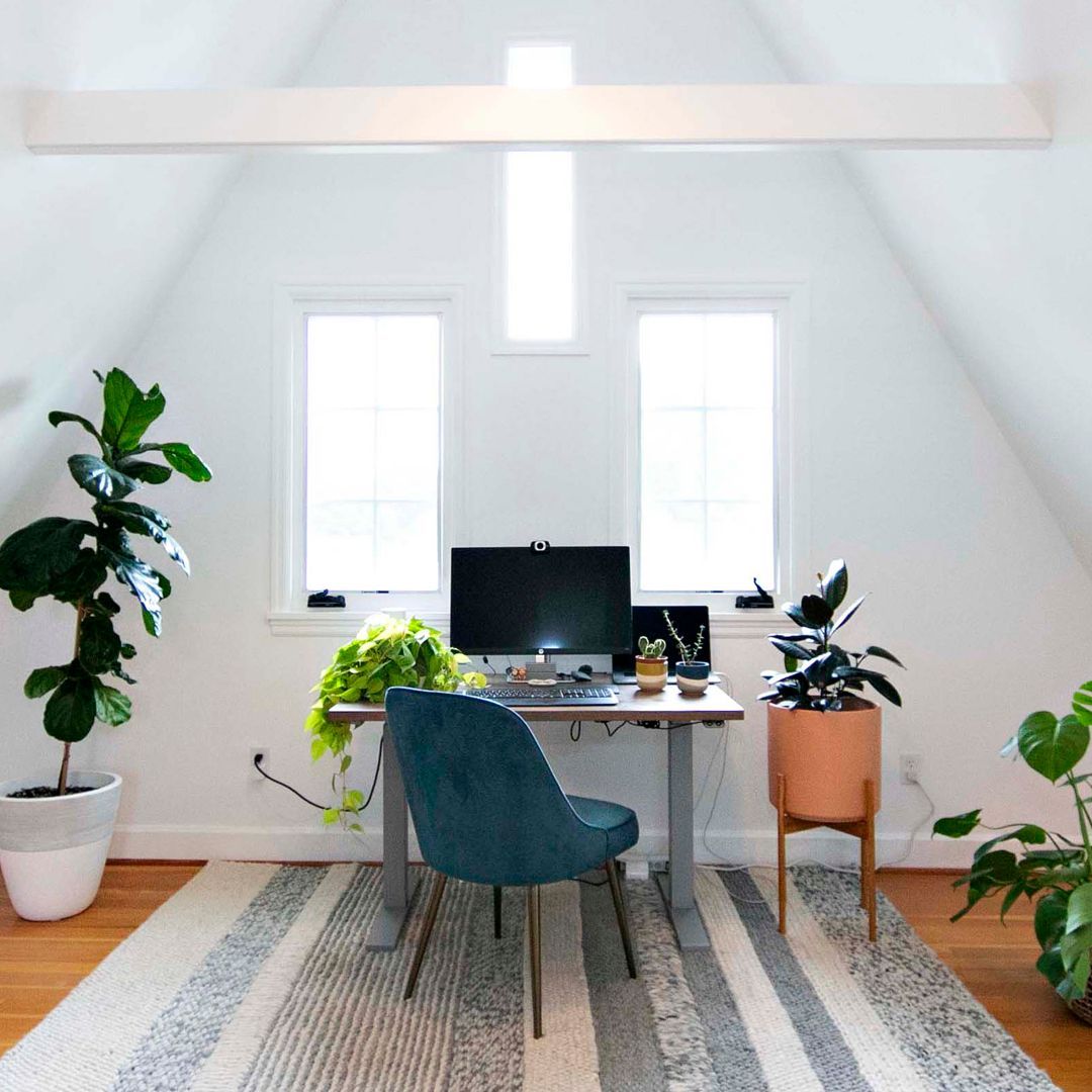 A-frame room painted in off white with desk and flower pots near the desk