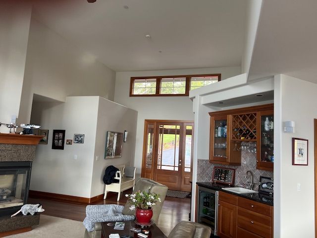 Interior view of a living room and entryway with clean, freshly painted off‑white walls and natural wood trim.