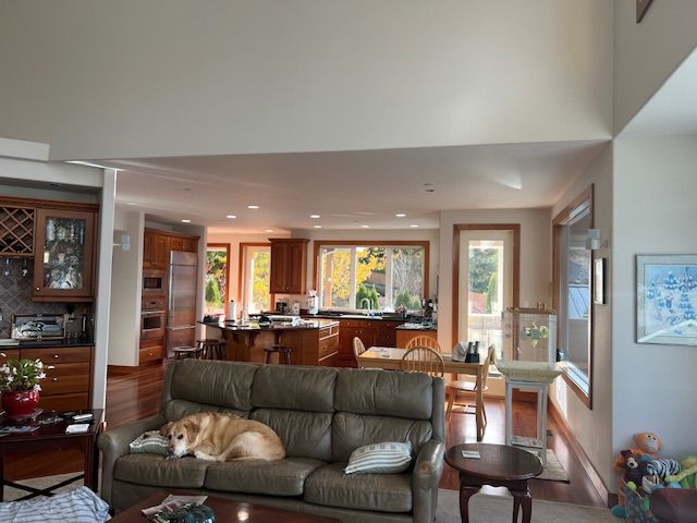 Neutral off-white walls complement wood trim and floors, creating a seamless transition between an open-concept living room and kitchen.