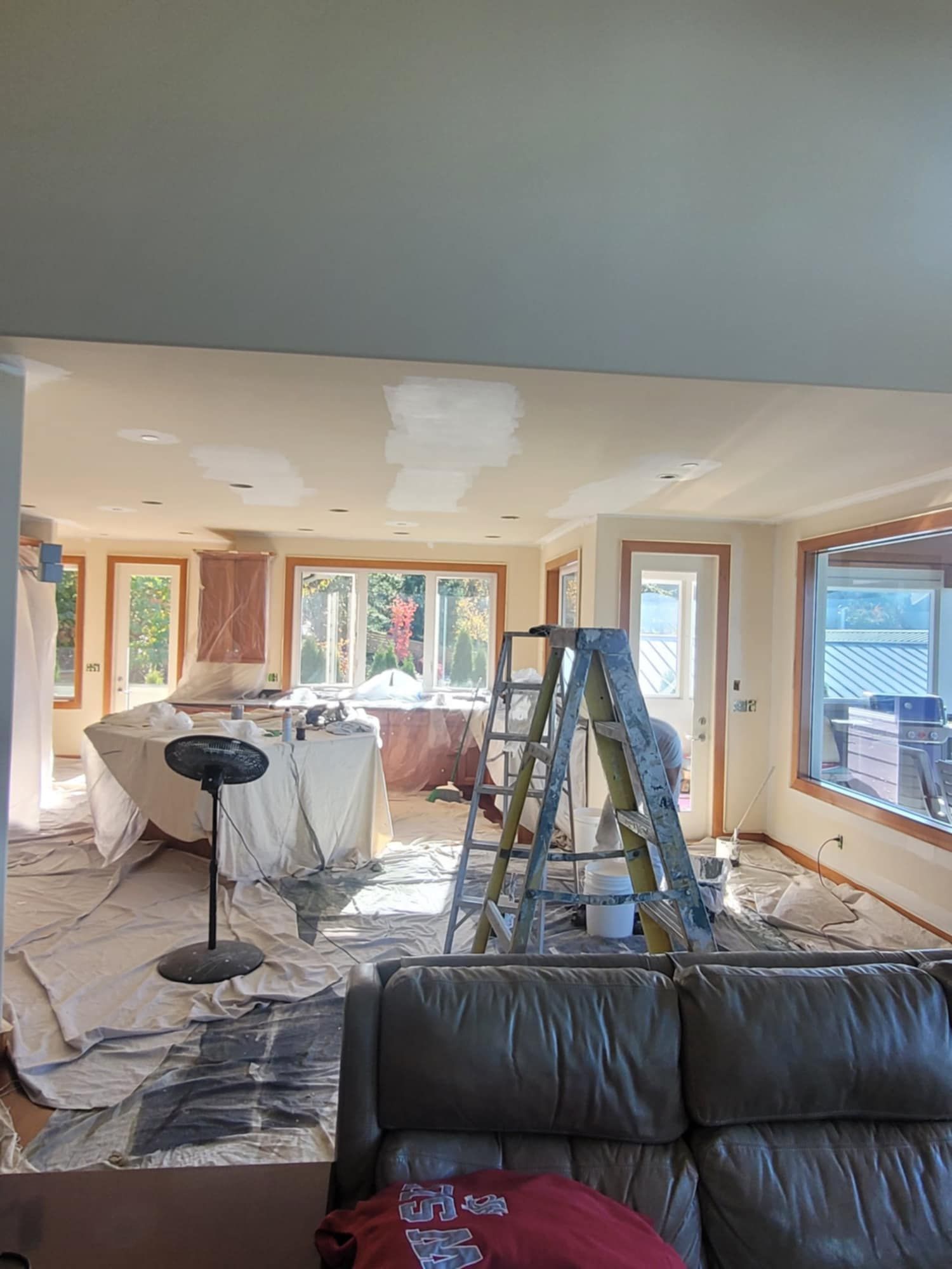 A room being prepared for an interior painting projectwith ceiling patchwork, drop cloths, and various tools set out.