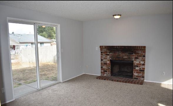 Refreshed living room with fireplace, sliding glass door, and newly‑painted white walls.