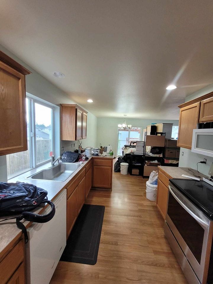 Kitchen with white painted walls, wood cabinets, laminate flooring, and stainless steel appliances.