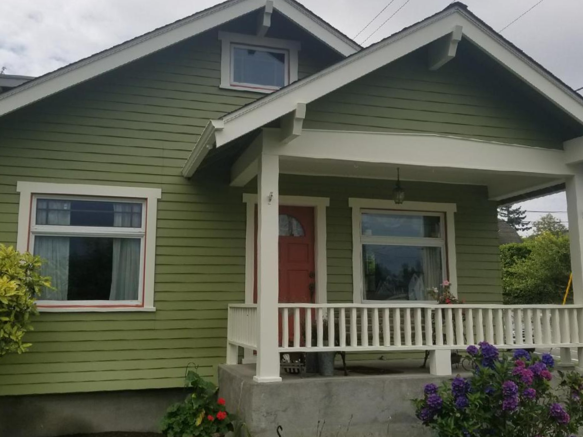 Two-story blue house with white trim and a red accent door.