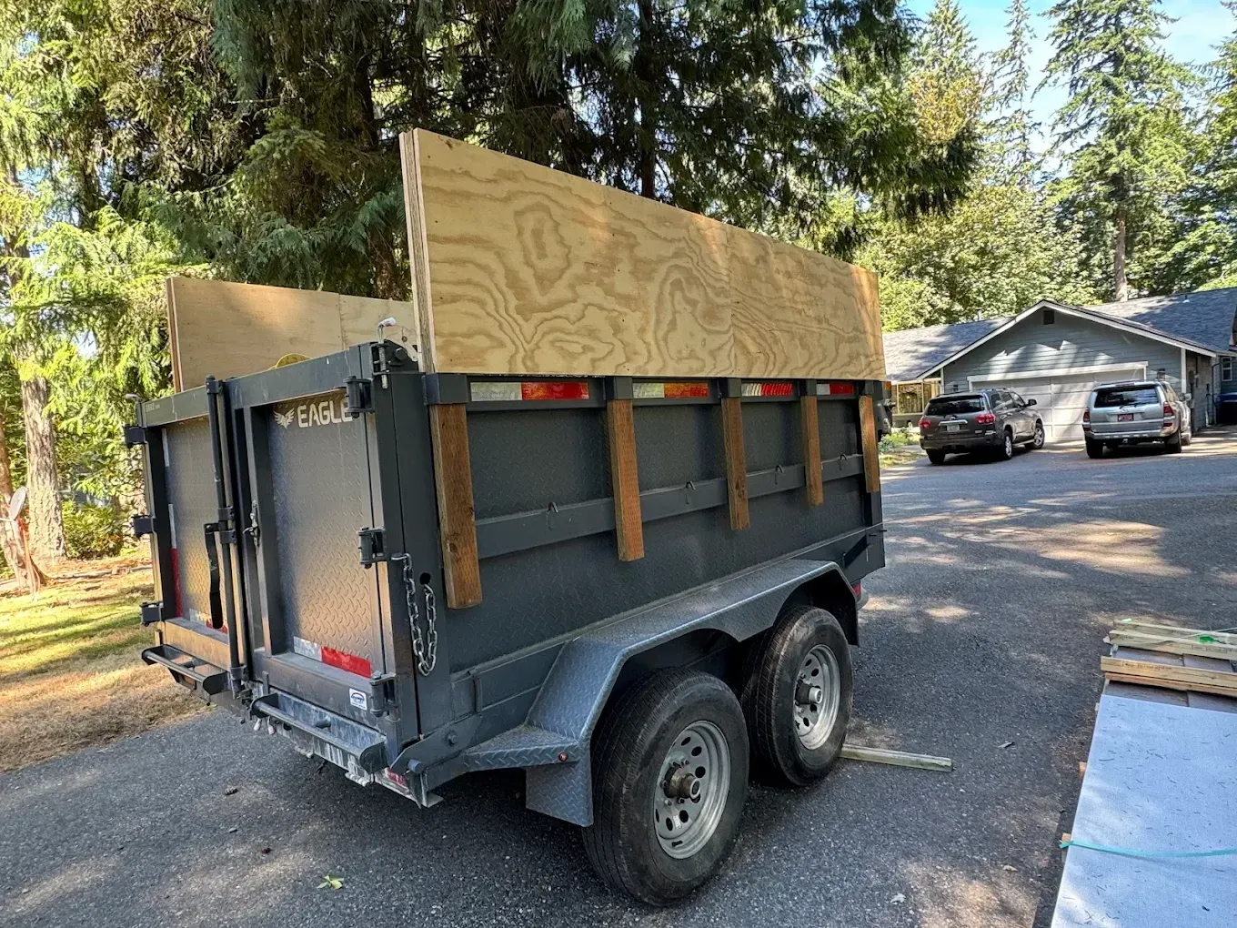 A dumpster trailer sits in the driveway of a home, waiting to be filled. 