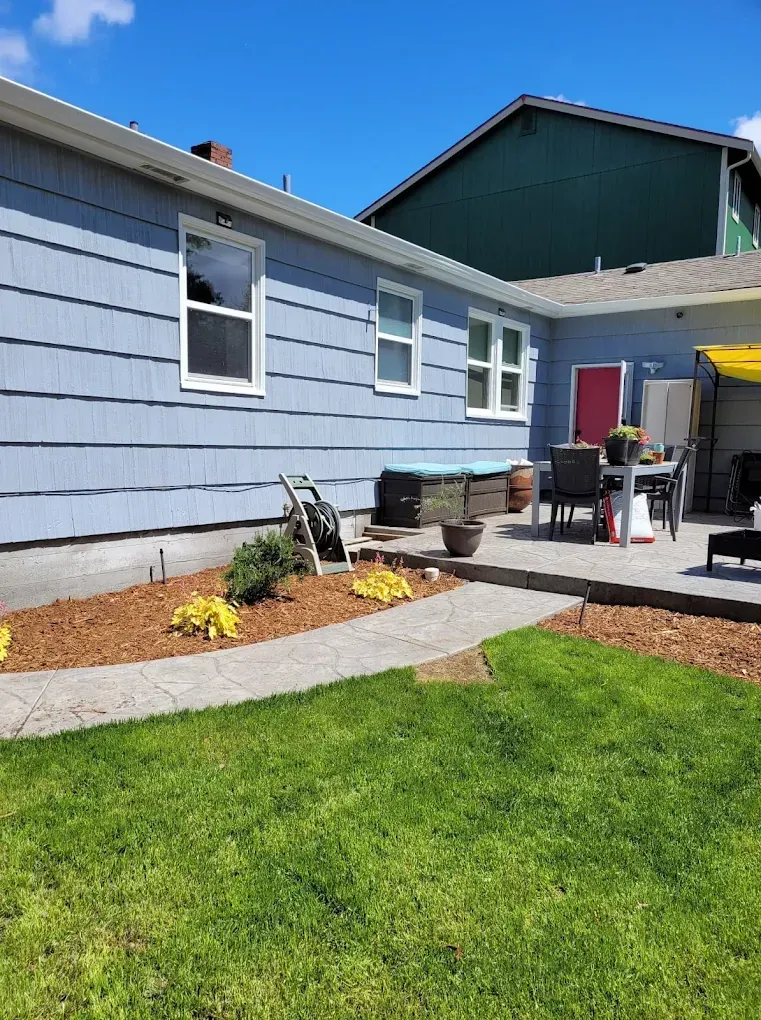 Blue house with back patio, walkway, and lawn.