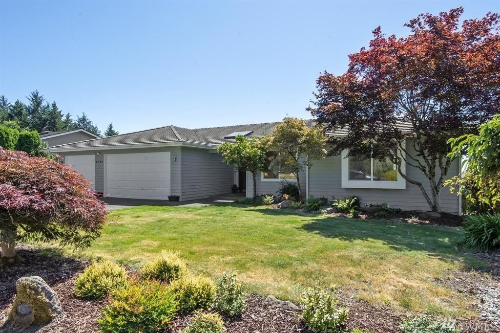 Single‑story home with light gray painted siding, white trim, and a well‑maintained front yard with mature trees.