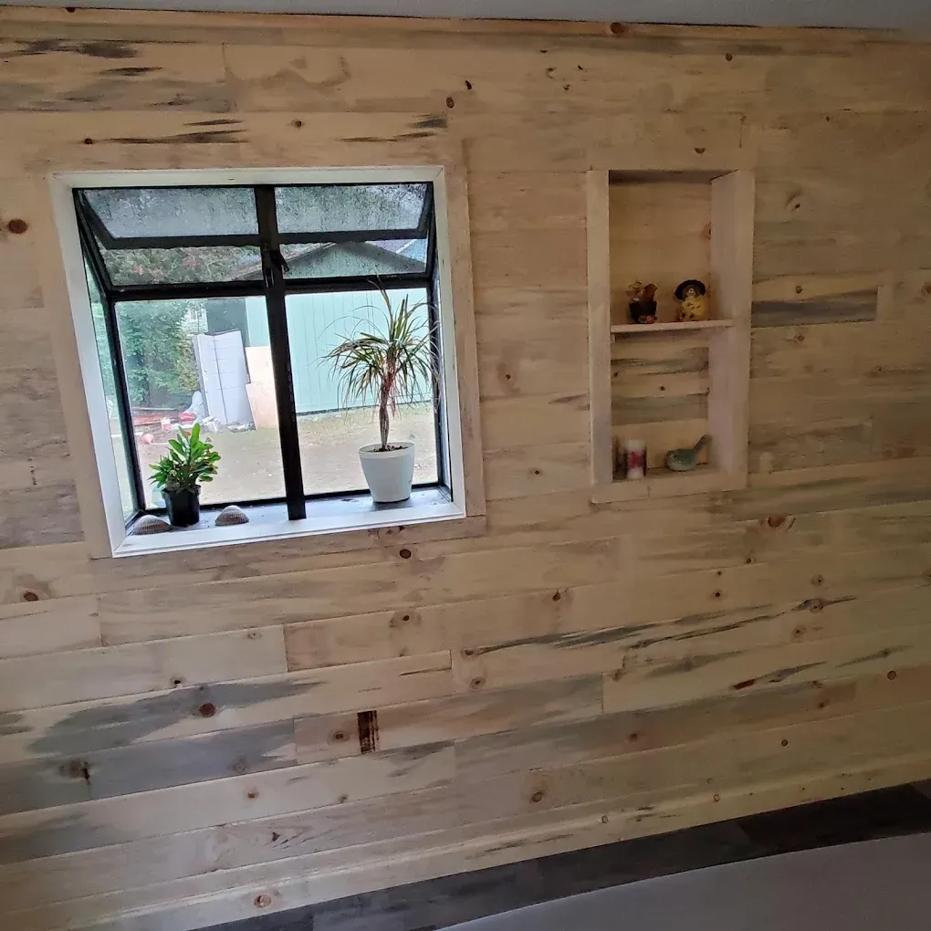 A custom wood‑paneled wall with a built‑in shelf and a window ledge holding potted plants.