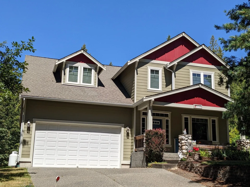 Two-story home with olive green siding, red gables, white trim, and new windows. 