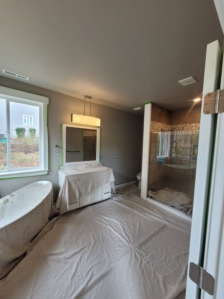 A bathroom is emptied with the floors and bathtub covered before an interior paint job. 