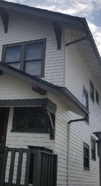 Gutters run along the eaves of a black and white two-story home. 