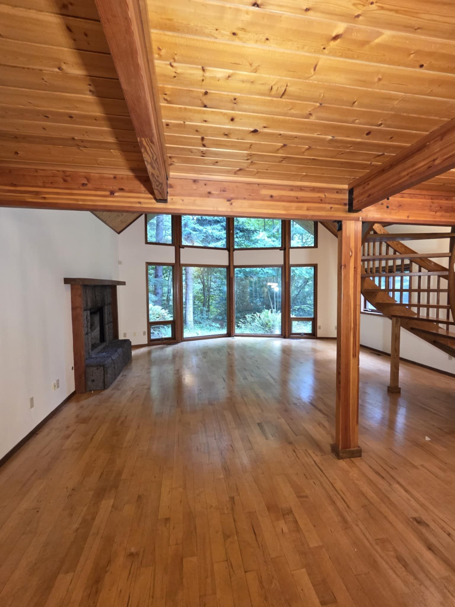 A view from under the loft looking out at a freshly-painted main room with a large wall of windows.