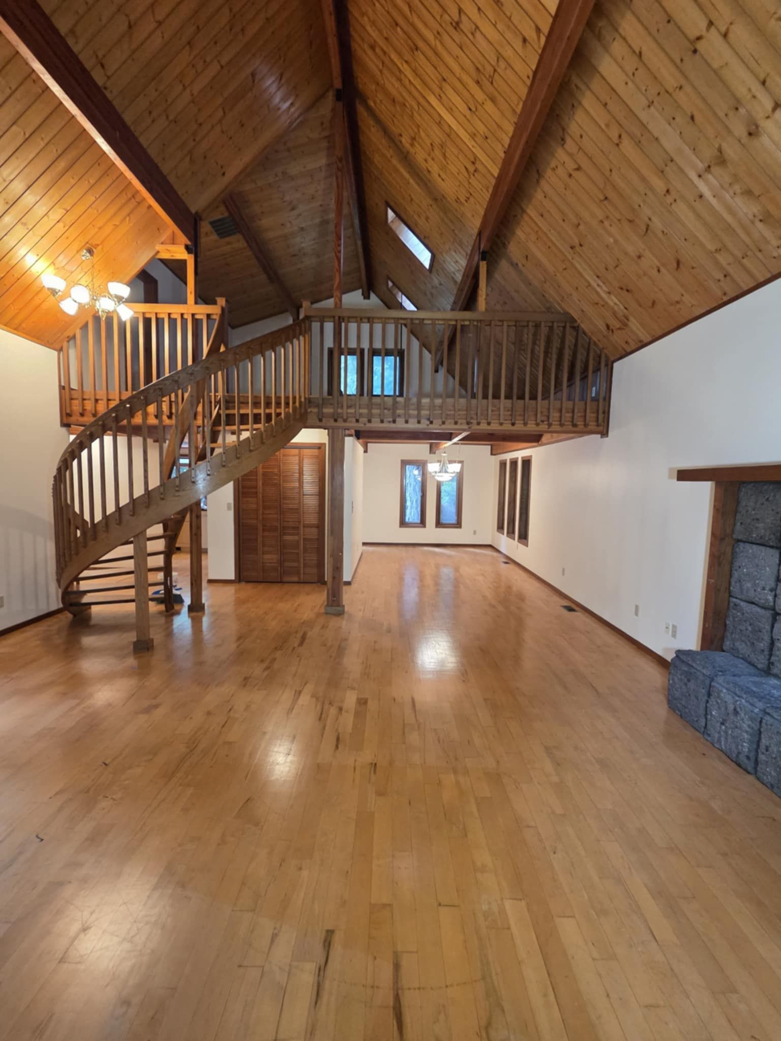 The fresh cream paint in a main room and loft compliments the shiplap ceiling and wood beams, foor, and railings.