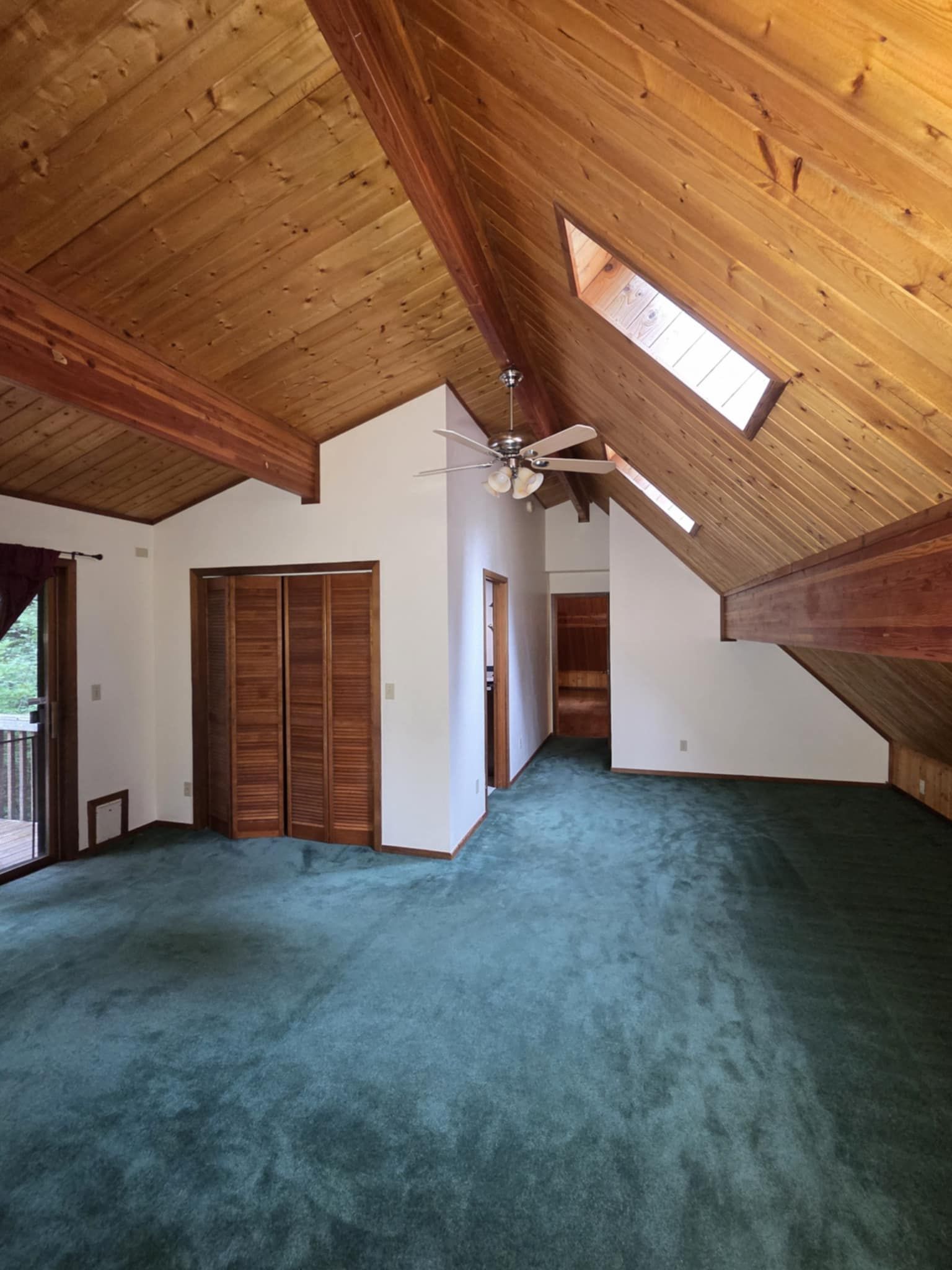 The upstairs loft in a freshly-painted cabin with shiplap ceilings and wooden beams, floors, and trim.