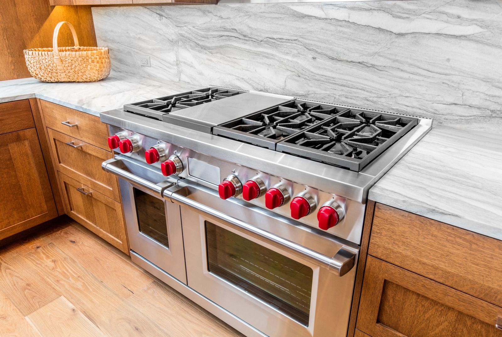 A stainless steel stove top oven is sitting on top of a marble counter top in a kitchen.
