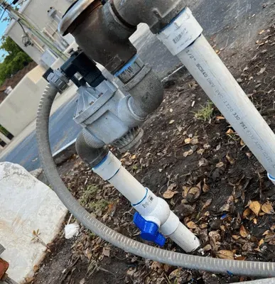 Irrigation system with a water valve and piping in an outdoor setting. The valve has a blue handle.