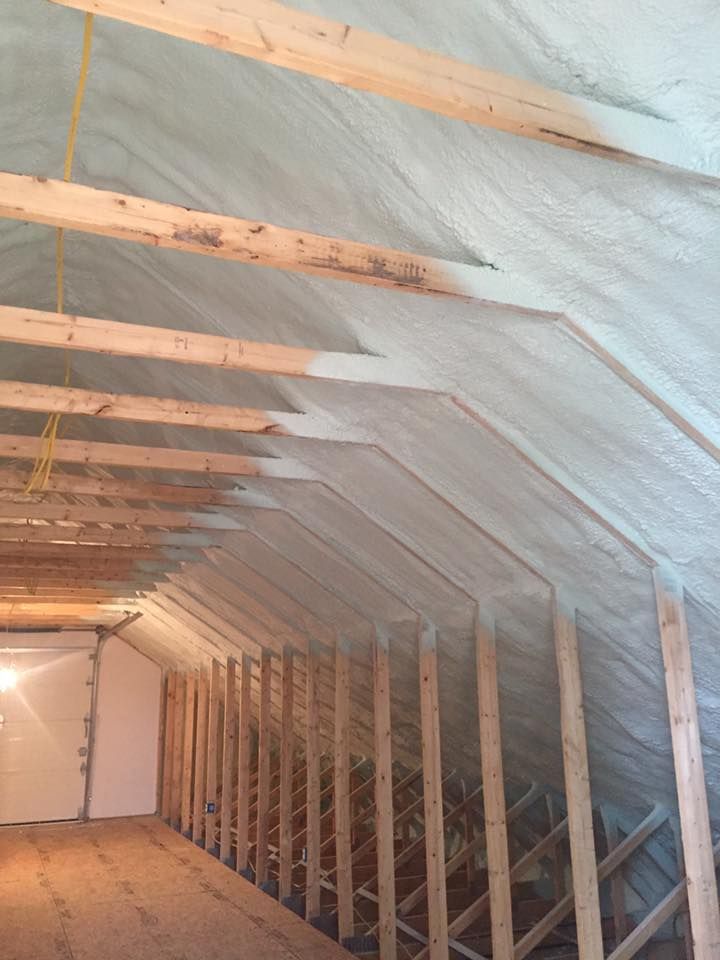 A room with wooden beams and a ceiling that is covered in spray foam.